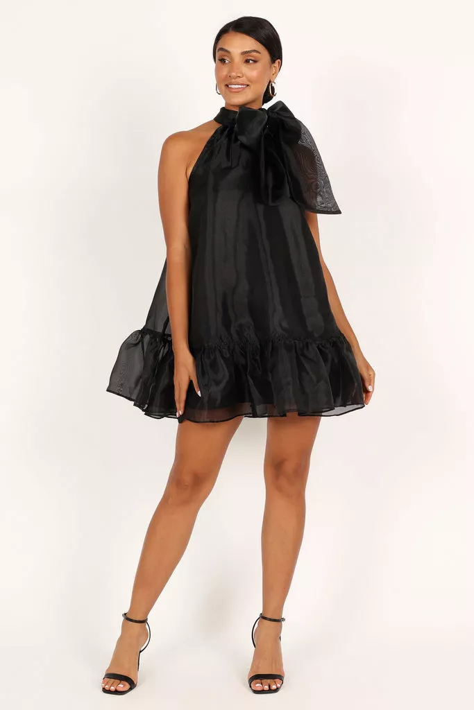 Modelul poarta o rochie neagra scurta, cu un decolteu pe cap si o funda atasata.