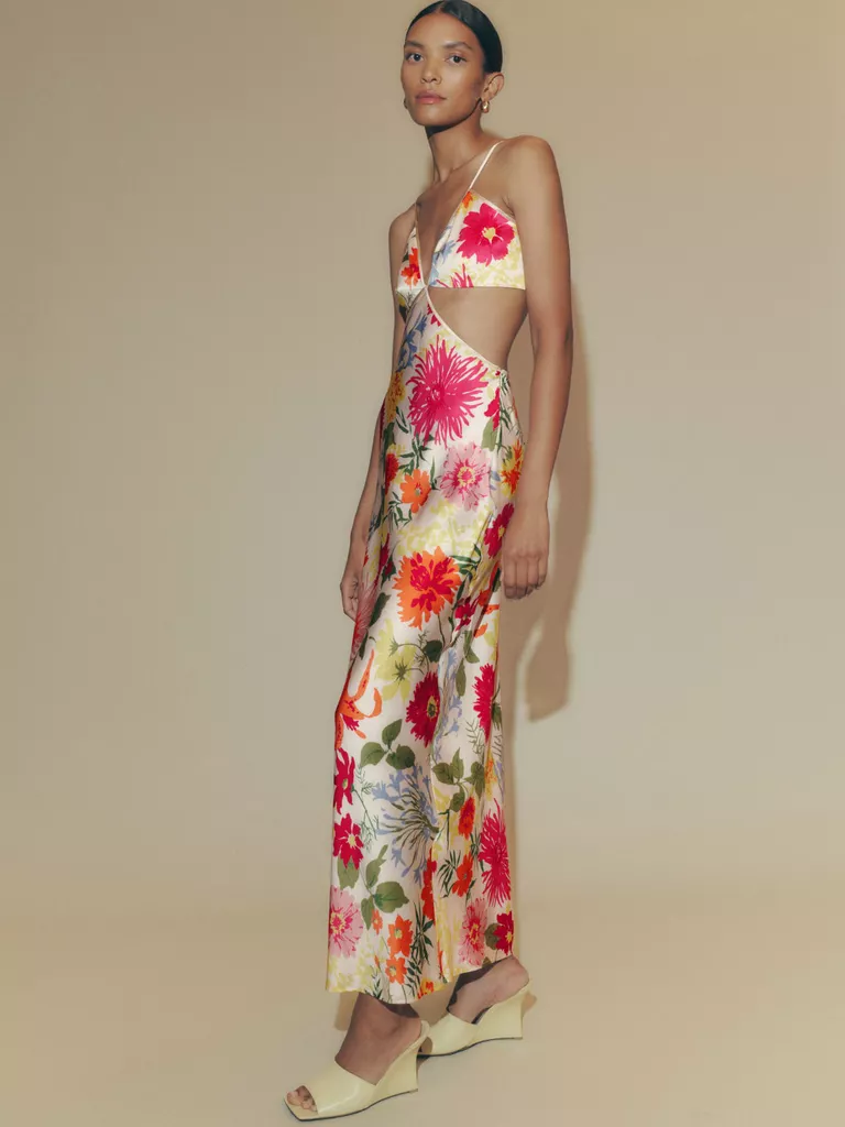 Modelul poarta o rochie de matase cu imprimeu floral, cu decupaje in jurul taliei.