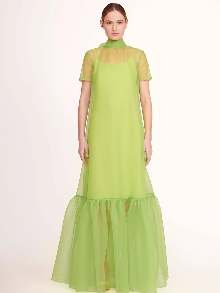 Modelul poarta o rochie verde Kelly cu tiv cu volane.