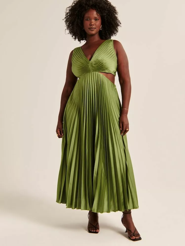 Modelul poarta o rochie de matase plisata de culoare verde smarald.
